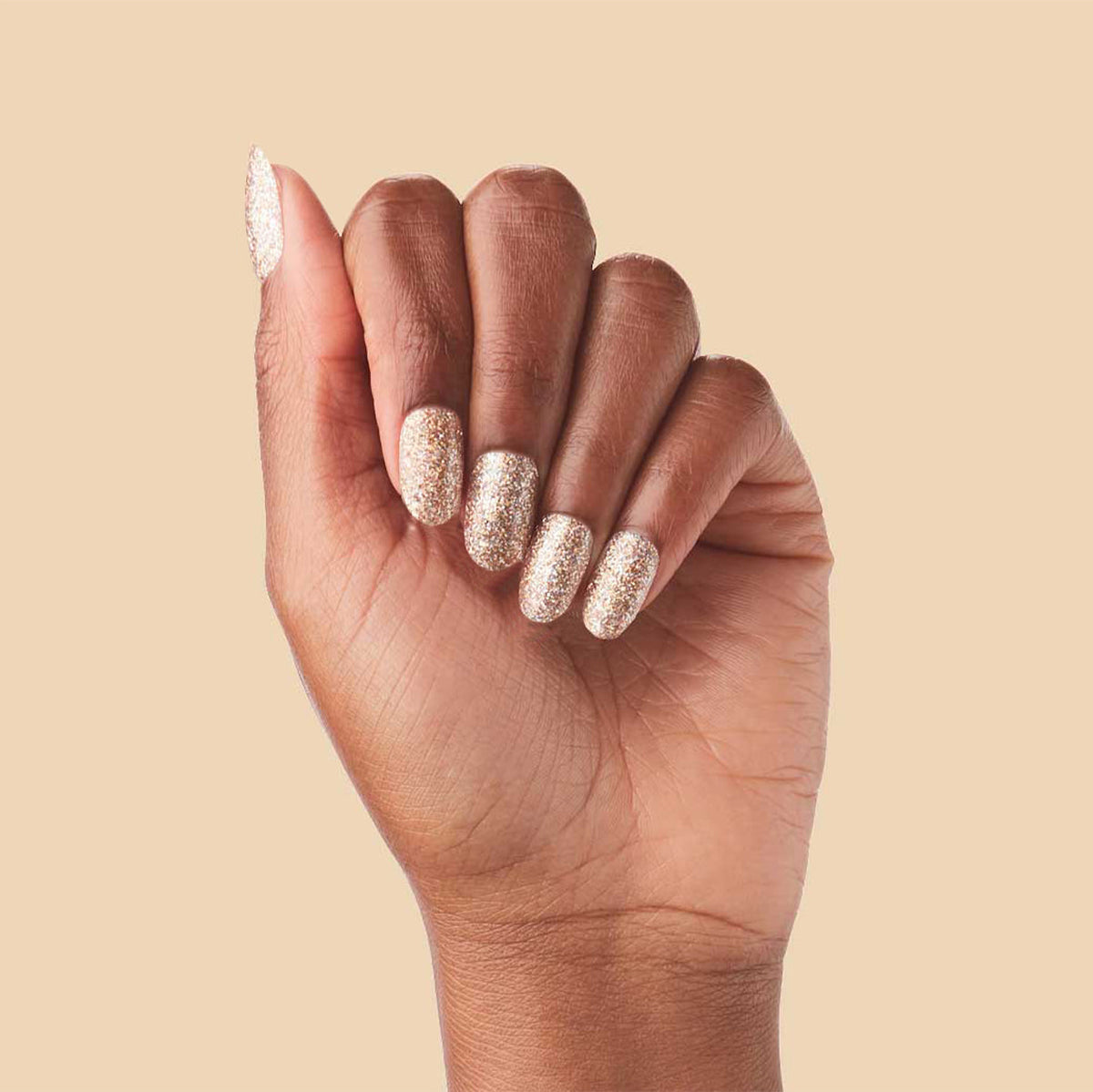 OBVI - Press-On | Medium | Oval hand showing medium oval false nails in shimmering gold glitter polish manicure